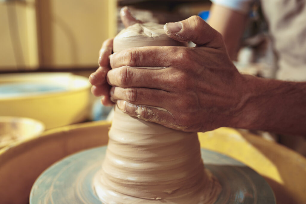 Creating a jar or vase of white clay close-up. Master crock. Man hands making clay jug macro. The sculptor in the workshop makes a jug out of earthenware closeup. Twisted potter